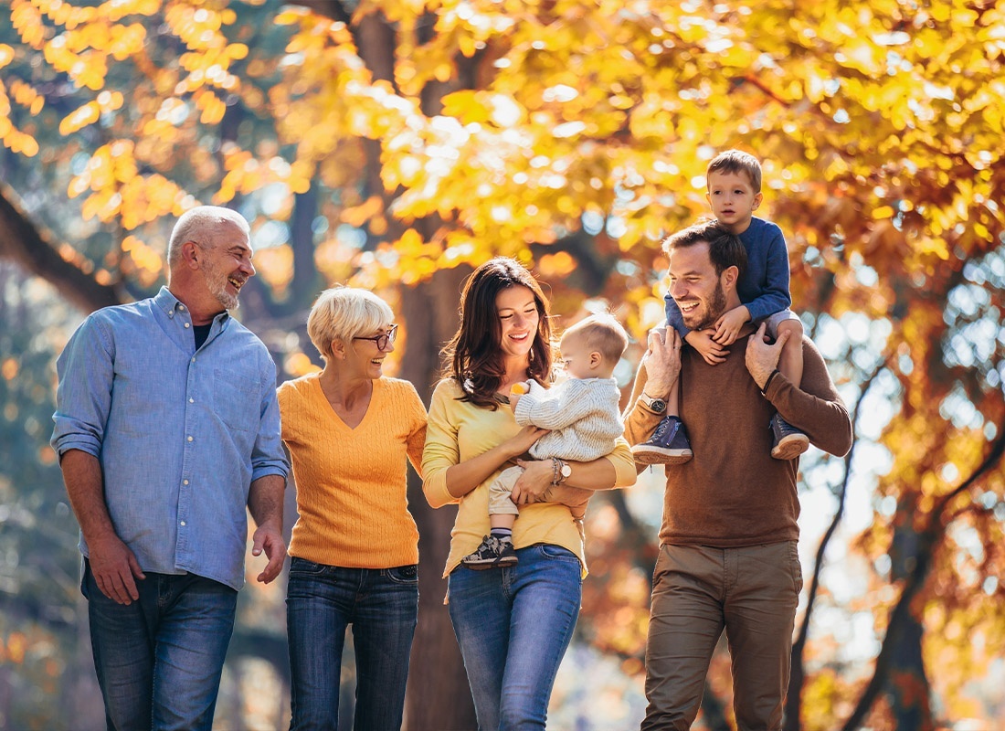 Insurance Solutions - Multi Generation Family Walking at the Park in Autumn Having Fun